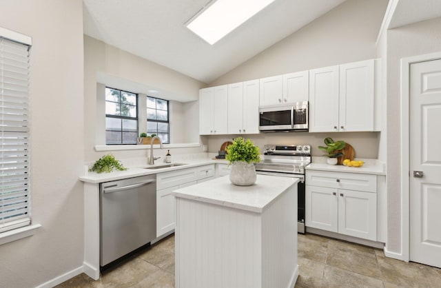 kitchen with appliances with stainless steel finishes, a center island, lofted ceiling, and white cabinetry