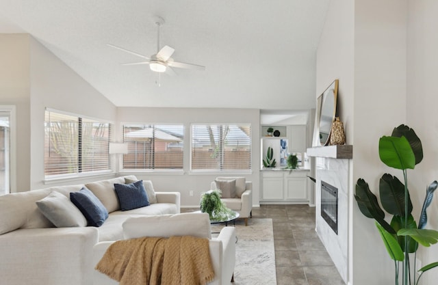 living area with a premium fireplace, ceiling fan, and high vaulted ceiling