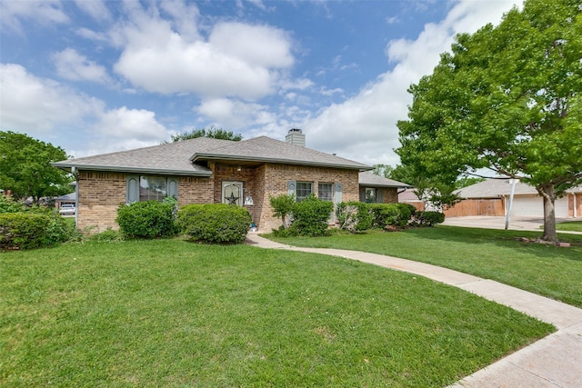 single story home featuring brick siding, a chimney, a shingled roof, and a front yard