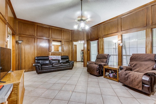 living area with light tile patterned floors, a ceiling fan, and a textured ceiling