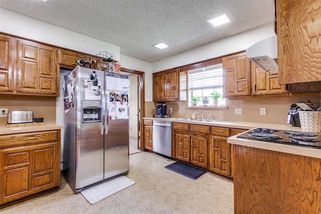 kitchen with a sink, appliances with stainless steel finishes, brown cabinets, and exhaust hood