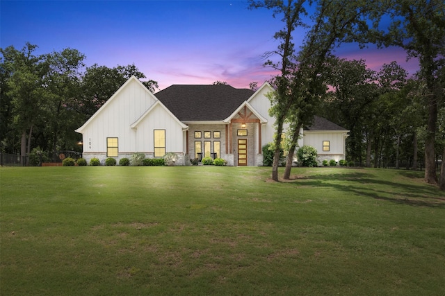 modern farmhouse with board and batten siding, a shingled roof, and a front lawn