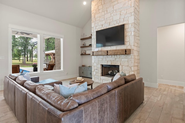 living room with baseboards, light wood-style floors, high vaulted ceiling, and a fireplace