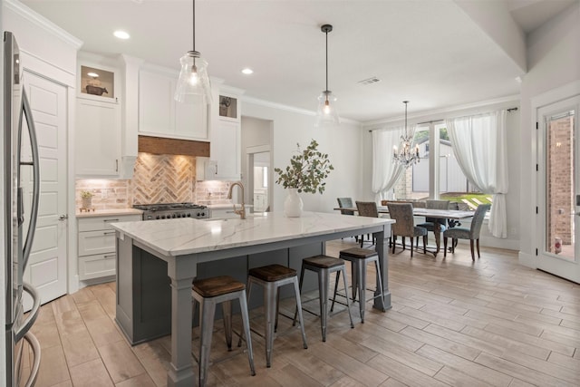 kitchen featuring decorative backsplash, stove, a kitchen breakfast bar, stainless steel fridge, and a sink
