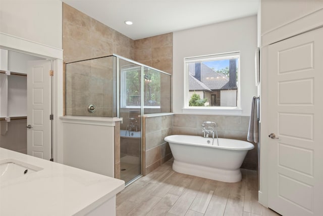 bathroom featuring tile walls, a soaking tub, a stall shower, and wood finished floors