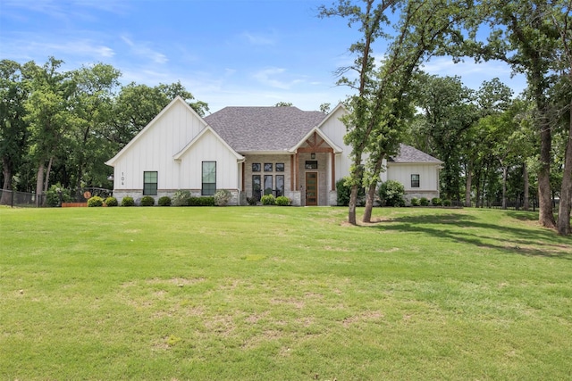 modern farmhouse featuring a front lawn, roof with shingles, fence, and board and batten siding