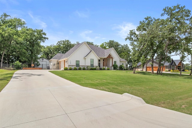 view of front of property with fence, an attached garage, board and batten siding, a front yard, and concrete driveway