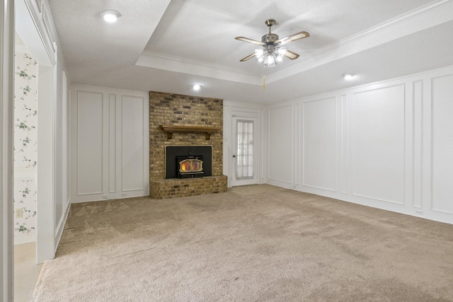 unfurnished living room with carpet flooring, ceiling fan, a raised ceiling, a decorative wall, and ornamental molding