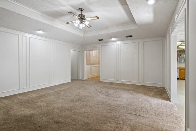 unfurnished bedroom featuring a tray ceiling, visible vents, light carpet, and a decorative wall