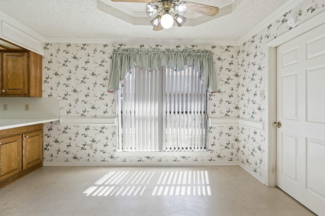 unfurnished dining area featuring crown molding, baseboards, a ceiling fan, and wallpapered walls