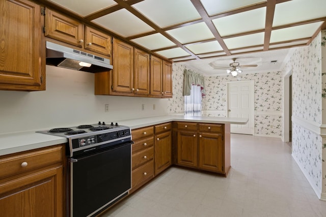 kitchen with brown cabinetry, under cabinet range hood, black electric range, and wallpapered walls
