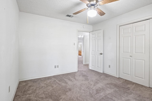 unfurnished bedroom with carpet flooring, a textured ceiling, baseboards, visible vents, and a closet
