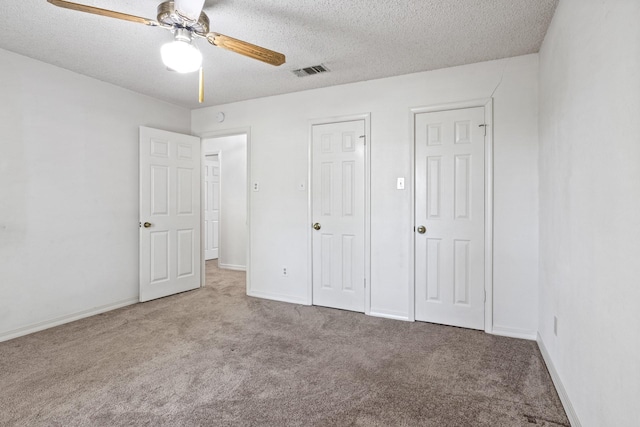 unfurnished bedroom with visible vents, a textured ceiling, carpet, and baseboards