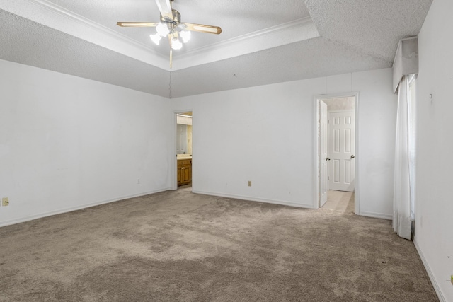 empty room featuring a raised ceiling, light carpet, a ceiling fan, and a textured ceiling