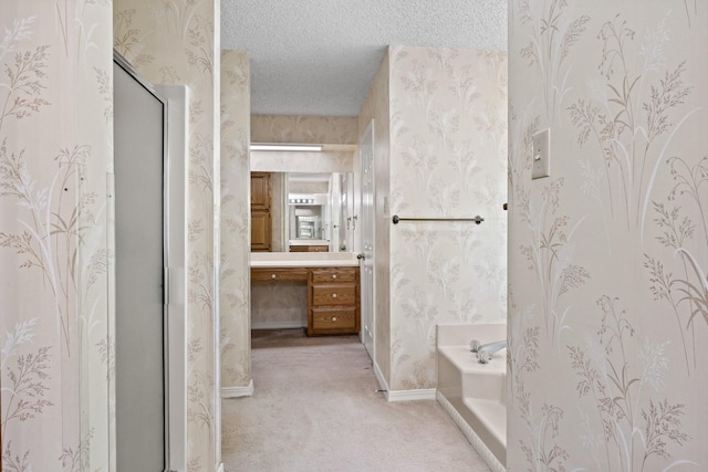 full bath featuring a garden tub, a textured ceiling, vanity, baseboards, and wallpapered walls