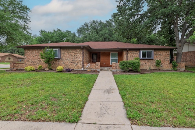 single story home with brick siding, a front yard, and a porch