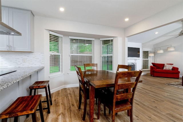 dining room featuring recessed lighting, light wood-style flooring, baseboards, and a fireplace