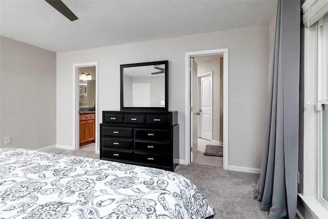 bedroom with baseboards, ensuite bath, and light carpet