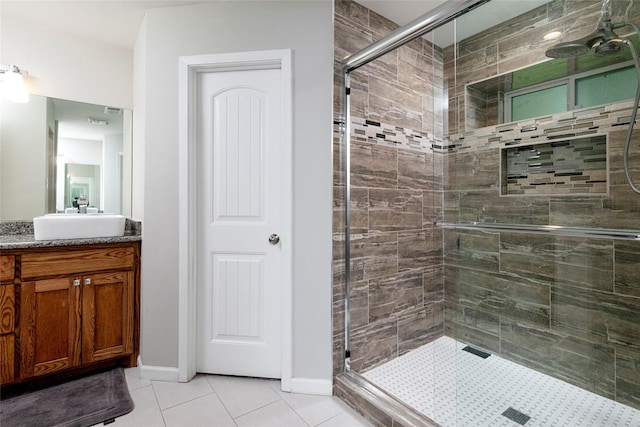 bathroom with vanity, tile patterned flooring, baseboards, and a shower stall