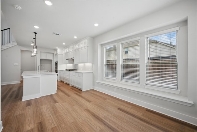 1851 Rosedale Ave, Van Alstyne, TX 75495 - kitchen with light wood finished floors, decorative light fixtures, plenty of natural light, and white cabinets