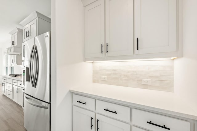 801 Daisy Corner Dr, Little Elm, TX 76227 - kitchen with stainless steel fridge with ice dispenser, tasteful backsplash, light countertops, white cabinets, and under cabinet range hood