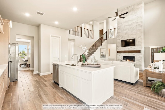 kitchen with visible vents, a sink, open floor plan, stainless steel appliances, and light wood-style flooring