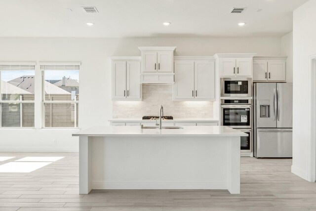 801 Daisy Corner Dr, Little Elm, TX 76227 - kitchen with stainless steel appliances, a sink, light countertops, backsplash, and light wood-type flooring