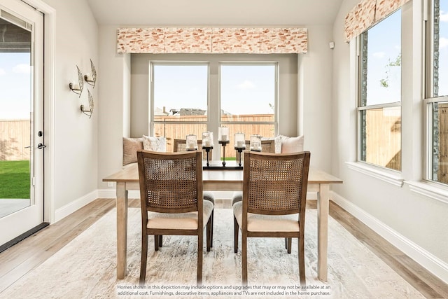 dining space with baseboards, plenty of natural light, and wood finished floors