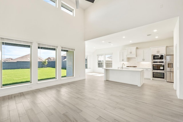 801 Daisy Corner Dr, Little Elm, TX 76227 - unfurnished living room with a sink, light wood-type flooring, a high ceiling, and recessed lighting