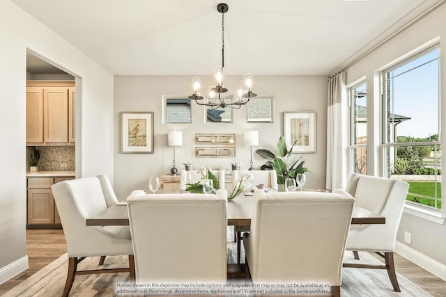 dining room featuring an inviting chandelier, light wood-style flooring, and baseboards