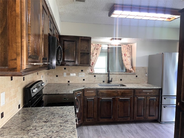 1005 Bass Dr, Plano, TX 75025 - kitchen with dark brown cabinetry, backsplash, light stone countertops, a sink, and stainless steel appliances