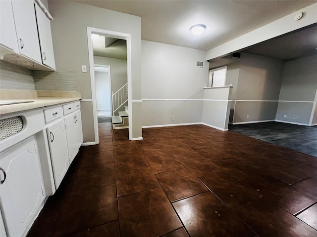 interior space featuring baseboards, visible vents, stairway, and dark tile patterned flooring