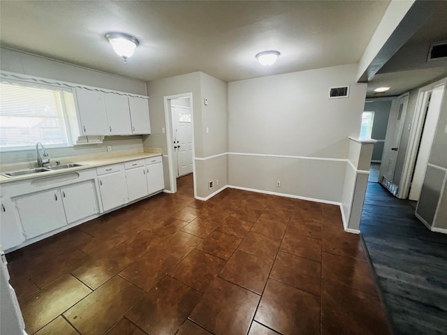 kitchen with a healthy amount of sunlight, visible vents, a sink, light countertops, and white cabinets