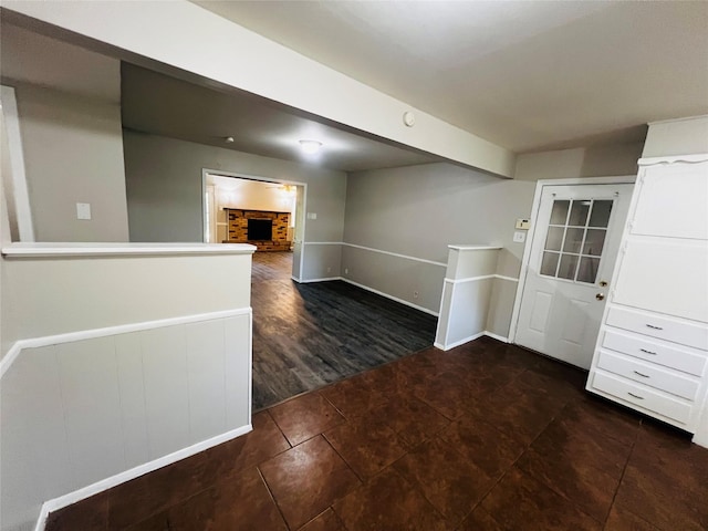 unfurnished room featuring baseboards, a fireplace, and dark tile patterned flooring