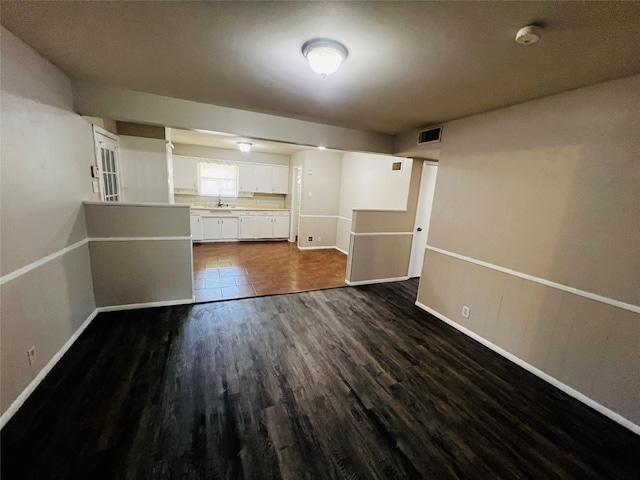 unfurnished living room featuring baseboards, dark wood-style flooring, and visible vents