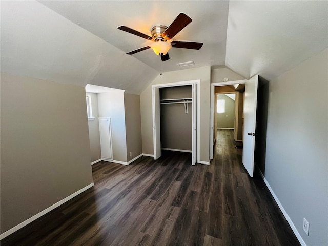 unfurnished bedroom featuring a ceiling fan, baseboards, dark wood-type flooring, vaulted ceiling, and a closet