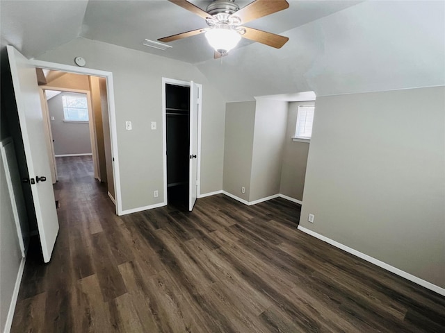 unfurnished bedroom featuring a ceiling fan, baseboards, dark wood finished floors, and lofted ceiling
