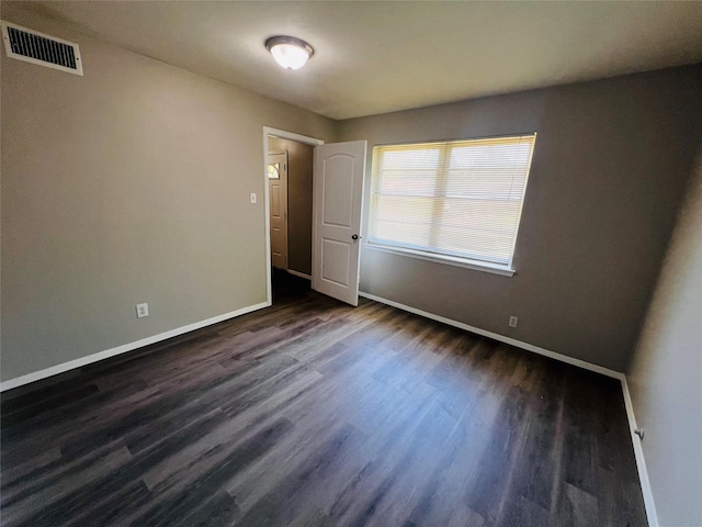 unfurnished room with visible vents, baseboards, and dark wood finished floors