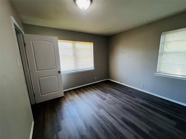 unfurnished room featuring baseboards and dark wood-style floors