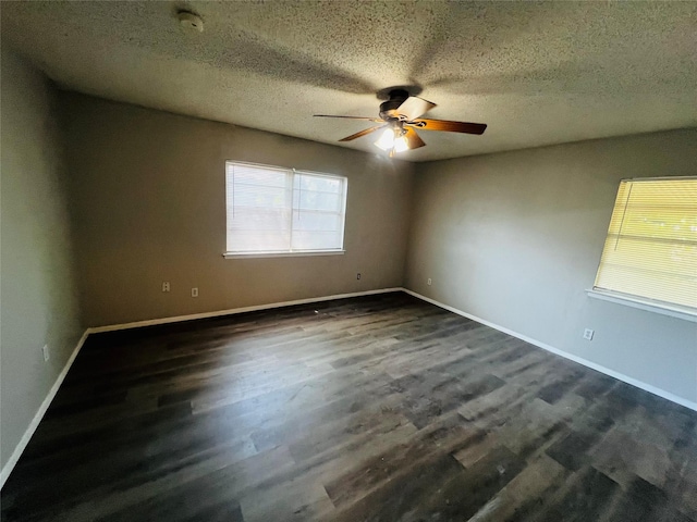 spare room with a textured ceiling, ceiling fan, dark wood finished floors, and baseboards