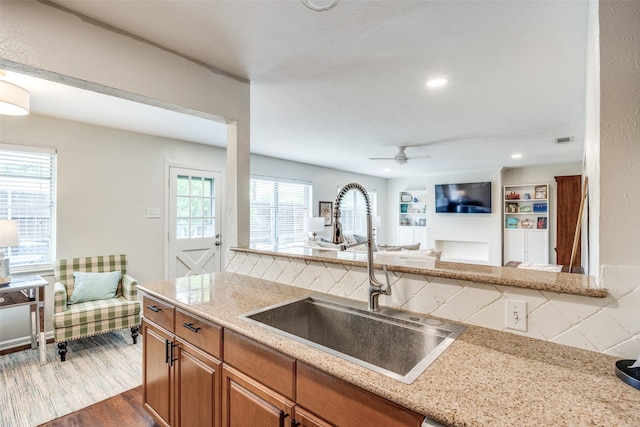 1200 Ridgeway Dr, Richardson, TX 75080 - kitchen featuring decorative backsplash, ceiling fan, brown cabinets, a sink, and dark wood-style floors