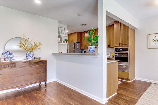 1200 Ridgeway Dr, Richardson, TX 75080 - kitchen with appliances with stainless steel finishes, a warming drawer, wood finished floors, light countertops, and brown cabinetry