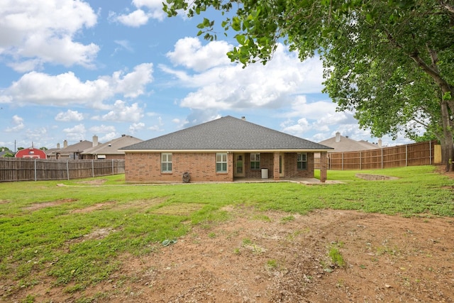 back of house featuring a yard, brick siding, and a fenced backyard