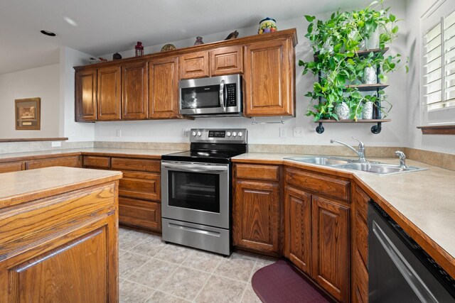 kitchen featuring brown cabinetry, a sink, appliances with stainless steel finishes, and light countertops