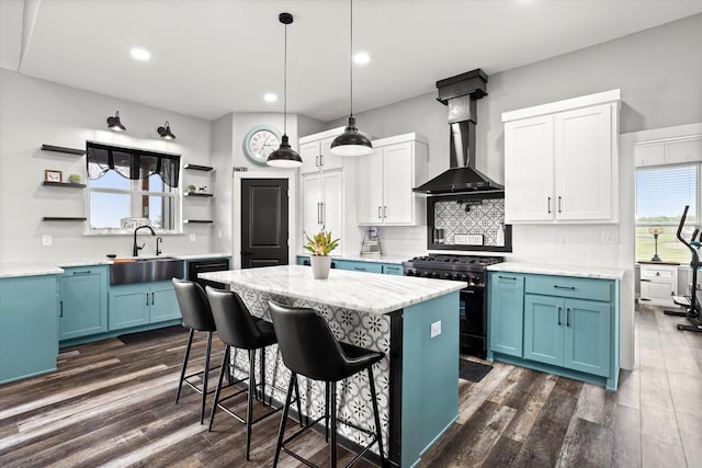 kitchen featuring open shelves, black gas range oven, wall chimney exhaust hood, and blue cabinets