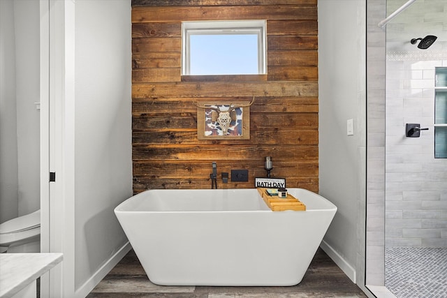 full bathroom with wood walls, a freestanding bath, wood finished floors, and a stall shower