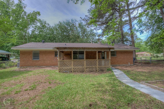 back of house with brick siding, fence, and a yard