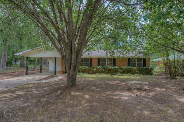 ranch-style home with brick siding, concrete driveway, fence, and a carport