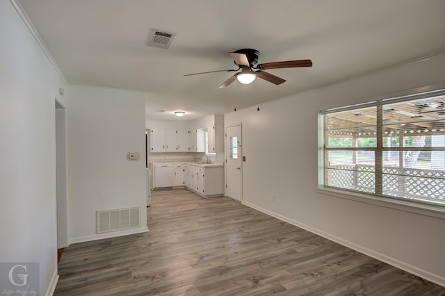 unfurnished living room featuring a sink, a healthy amount of sunlight, ceiling fan, and visible vents
