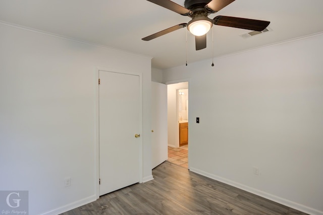 unfurnished bedroom with crown molding, a ceiling fan, baseboards, and wood finished floors
